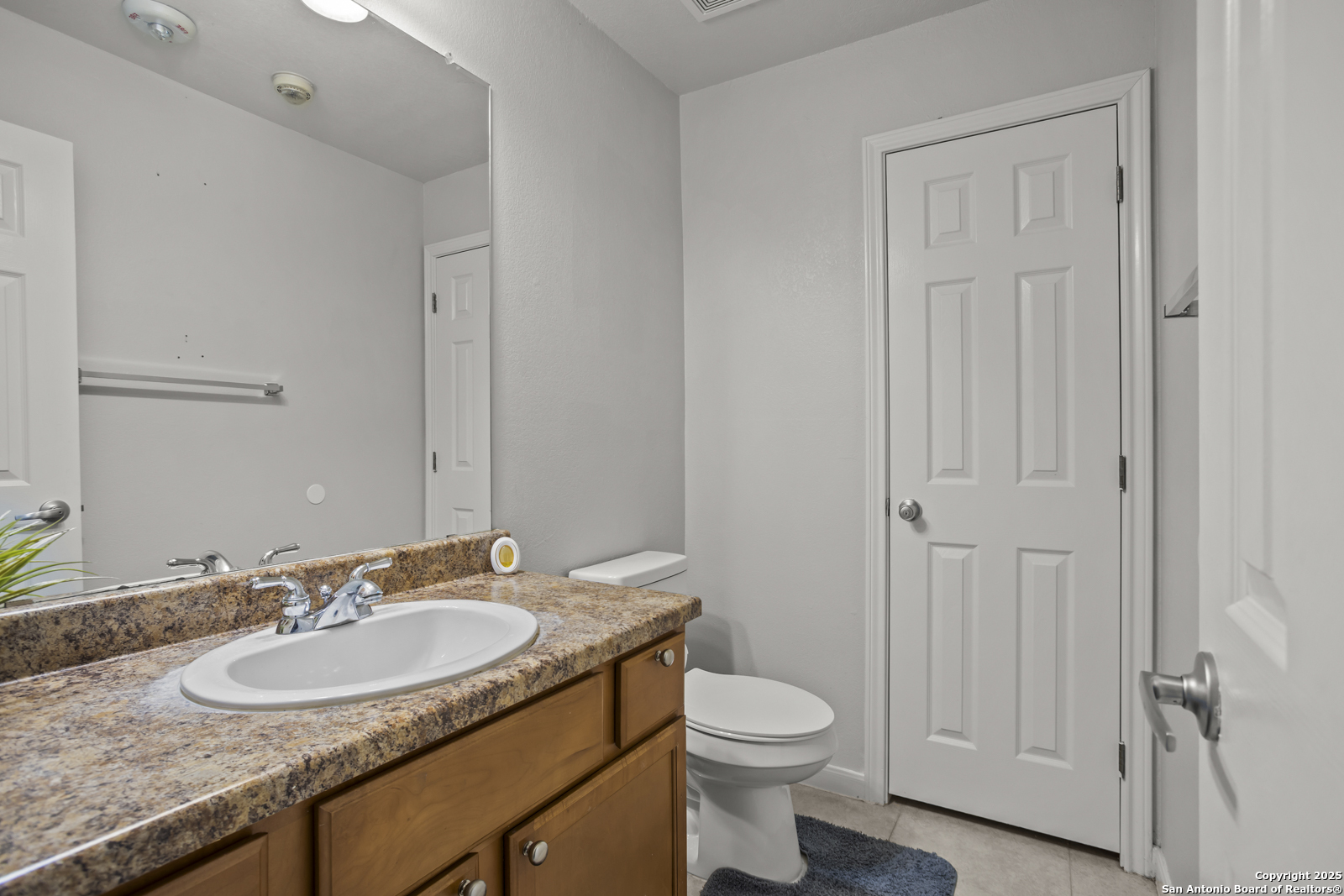 7323 Snowden Road, Unit 1102 San Antonio, TX 78229 - Photo 25 of 27 a bathroom with a granite countertop sink a toilet and a mirror