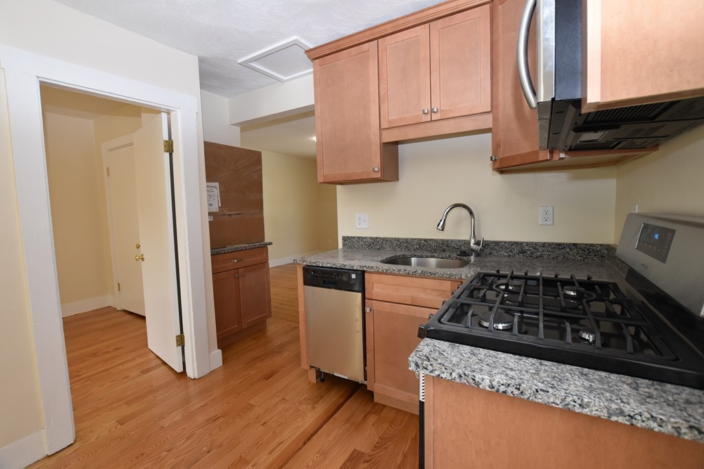 25 Sawin Street, Unit 25 Watertown, MA 02472 - Photo 6 of 22 a kitchen with granite countertop a stove and cabinets