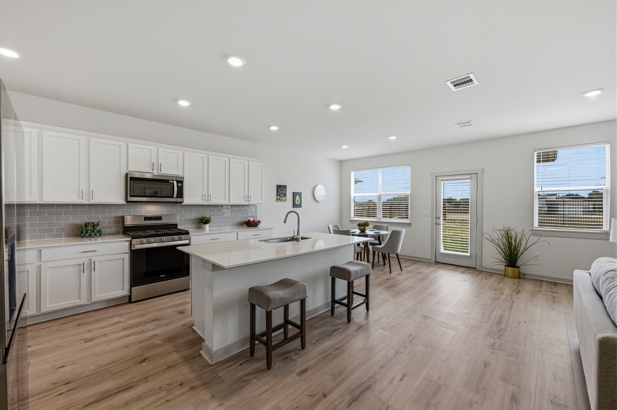 7511 Traylor Cove Austin, TX 78724 - Photo 2 of 40 a large kitchen with kitchen island a dining table chairs and a wooden floor