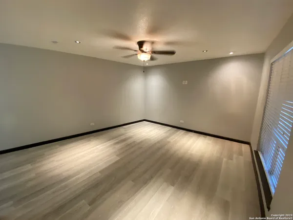 an empty room with wooden floor and fan
