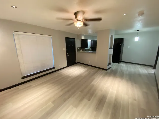a view of a livingroom with a stove wooden cabinets and a ceiling fan