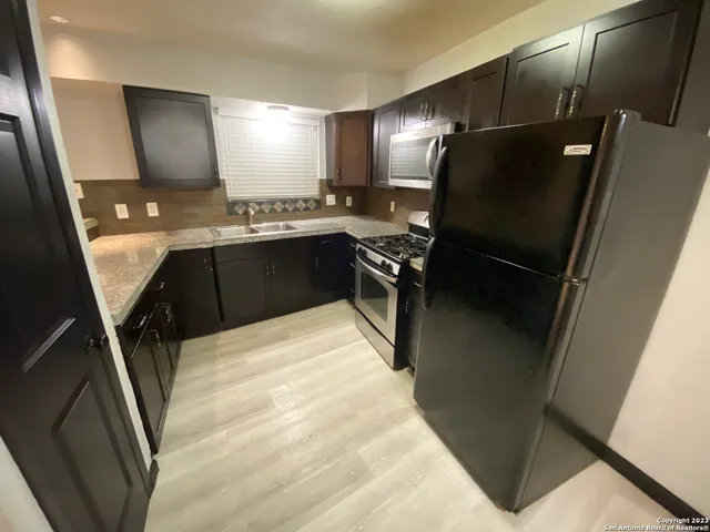 a kitchen with granite countertop a refrigerator a sink and stove