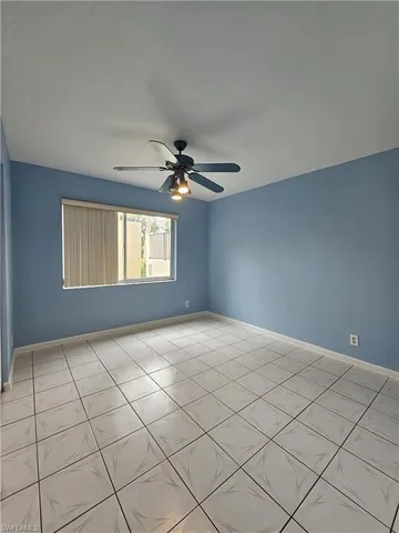 a view of an empty room and window and chandelier fan