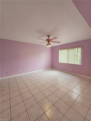 a view of an empty room with window and chandelier fan