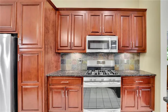 a kitchen with granite countertop wooden cabinets and a stove top oven