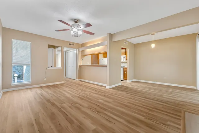 a view of an empty room with a window and wooden floor