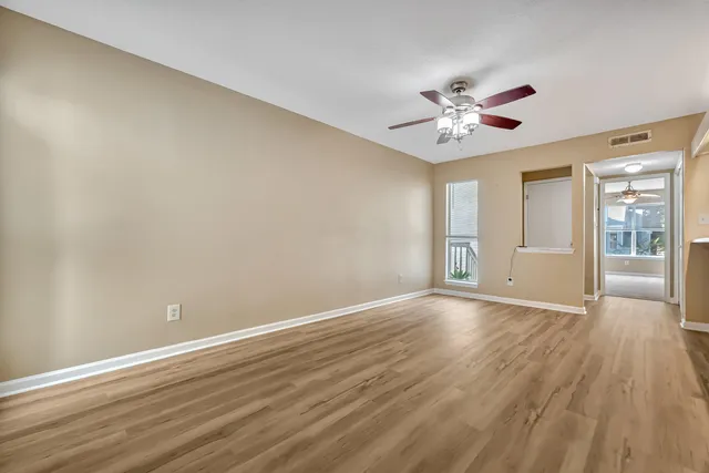 a view of an empty room with window and wooden floor