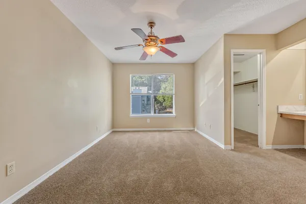 an empty room with windows and fan