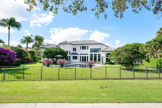 a view of a house in a big yard with plants and large trees