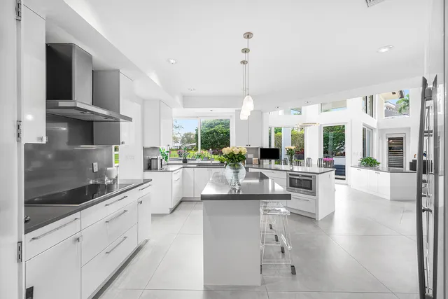 a large white kitchen with lots of counter space and chandelier