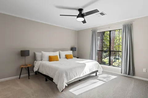 a bedroom with a bed a ceiling fan and a window