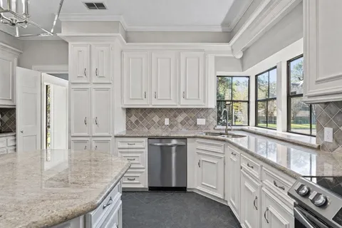 a kitchen with stainless steel appliances granite countertop a stove a sink and white cabinets
