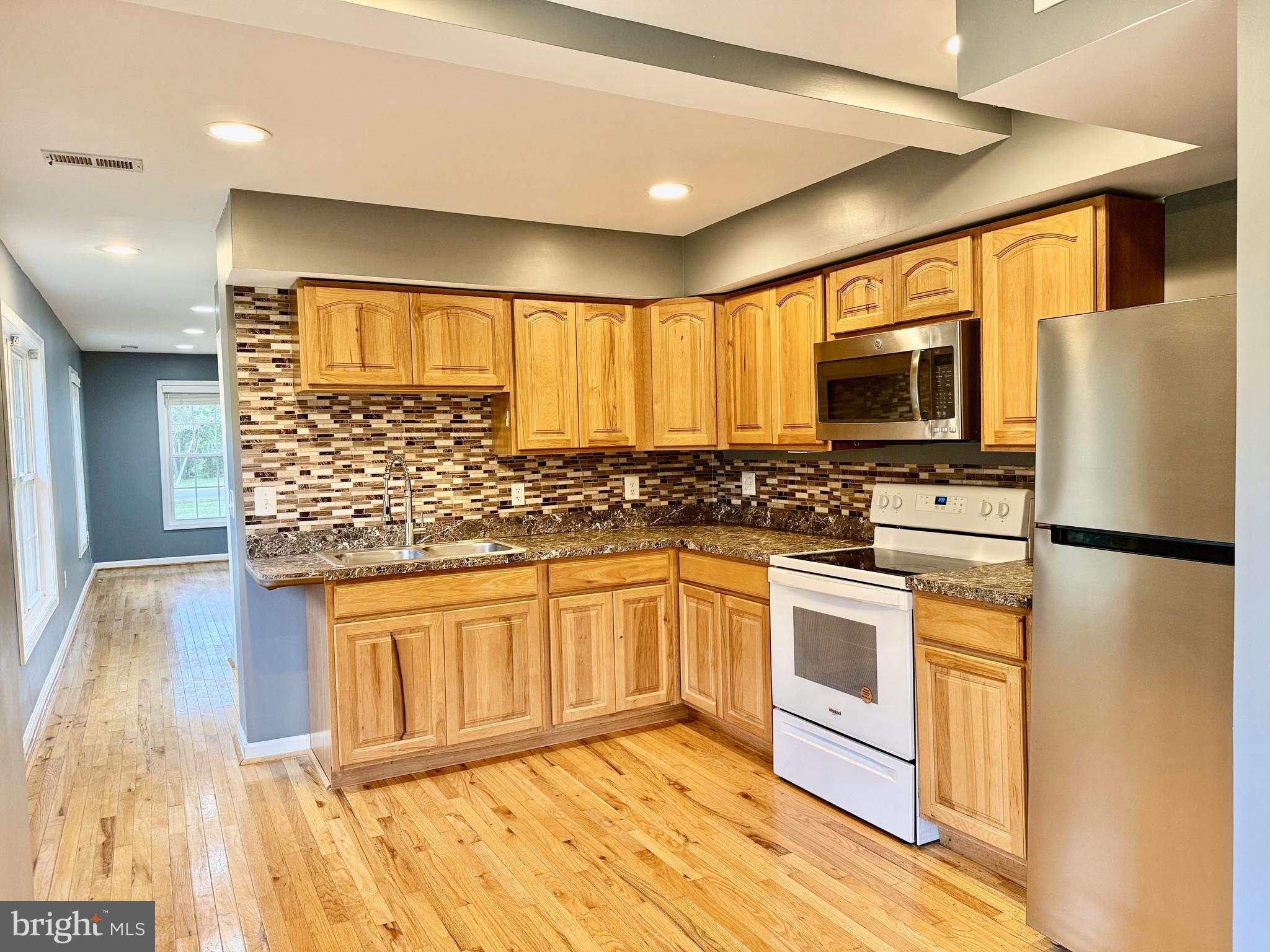 722 Hartwood Road Fredericksburg, VA 22406 - Photo 6 of 28 a kitchen with stainless steel appliances a stove a sink cabinets and a wooden floor