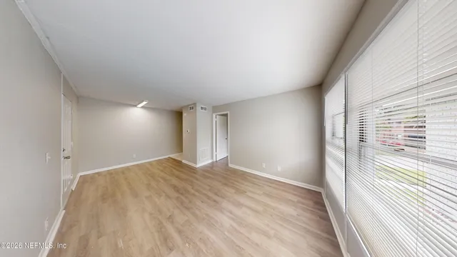 a view of empty room with wooden floor and fan