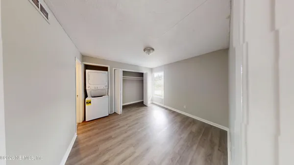 a view of an empty room with window and wooden floor