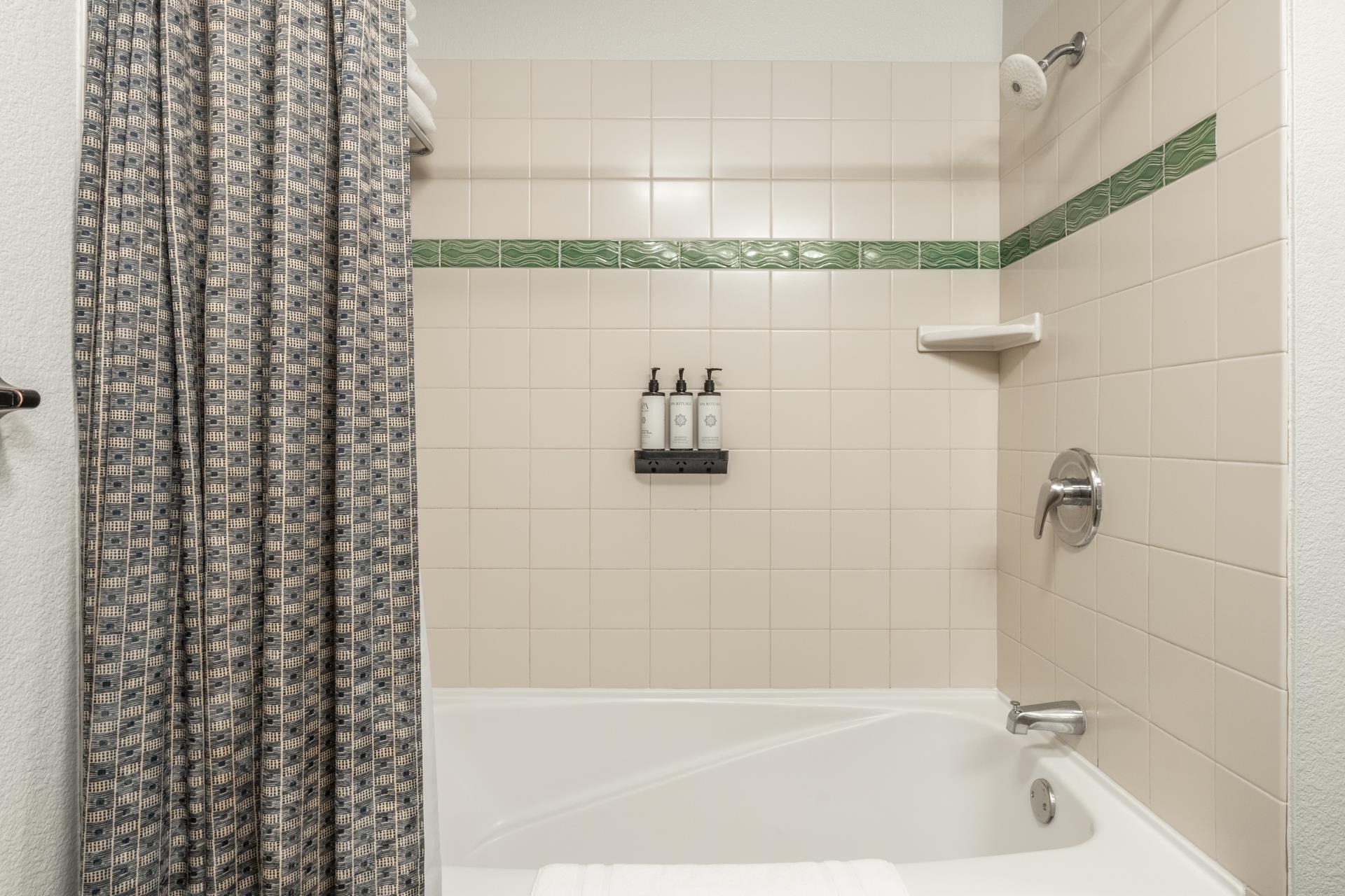 6201 Minaret Road, Unit 2328 Mammoth Lakes, CA 93546 - Photo 7 of 23 Bathtub with an integrated shower, tiled surround, and decorative accent tile band