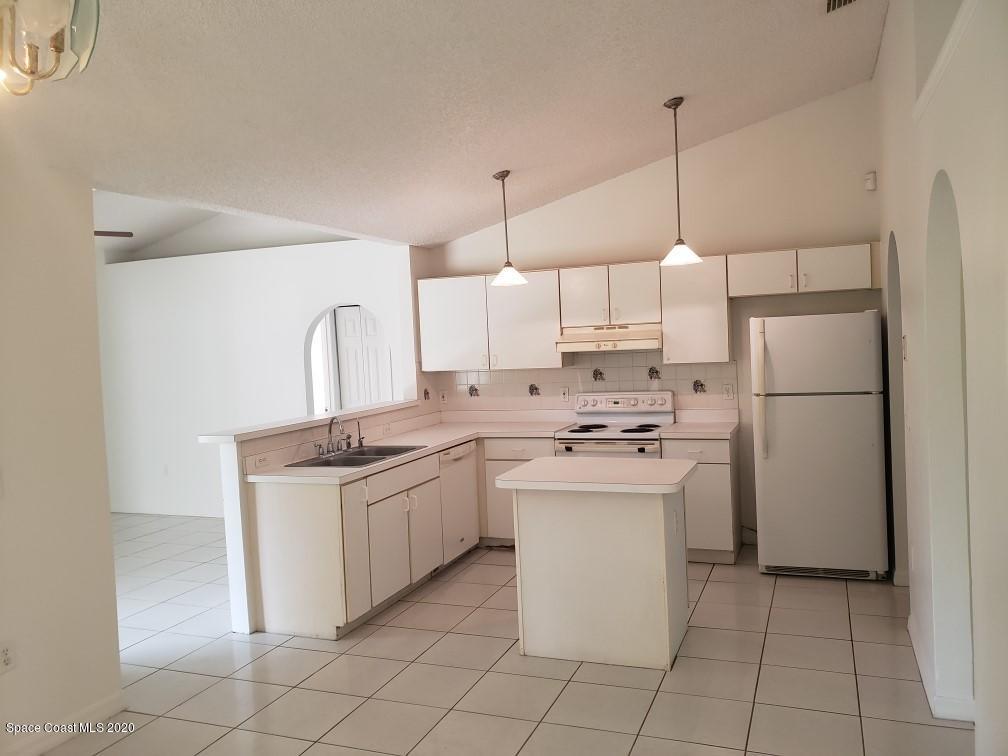 1280 Seabold Road Southwest Palm Bay, FL 32908 - Photo 8 of 28 a kitchen with kitchen island a sink a counter and a refrigerator