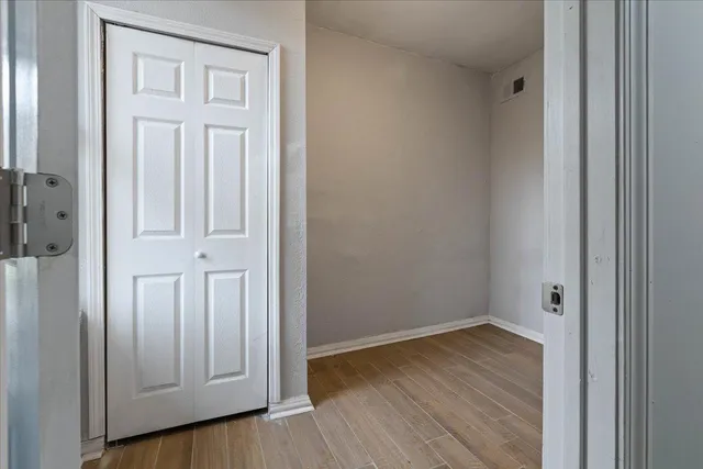 an empty room with wooden floor and closet area