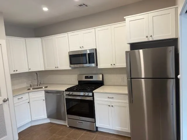a kitchen with white cabinets and stainless steel appliances