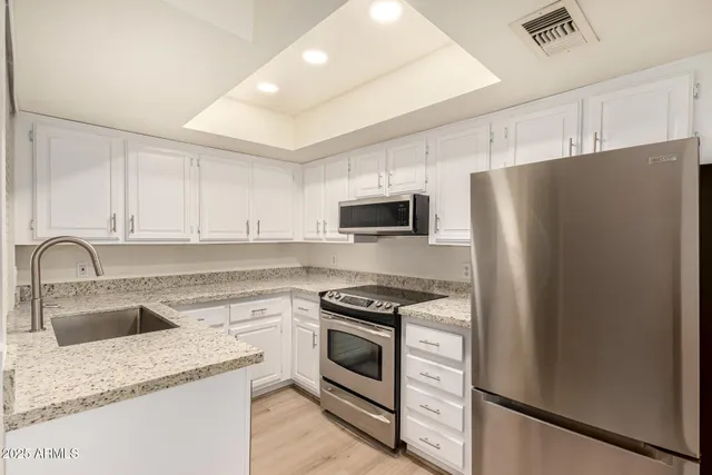 a kitchen with granite countertop white cabinets and stainless steel appliances