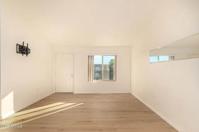 an empty room with wooden floor and windows