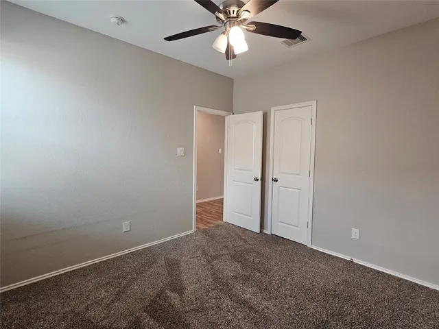 an empty room with closet and a chandelier fan