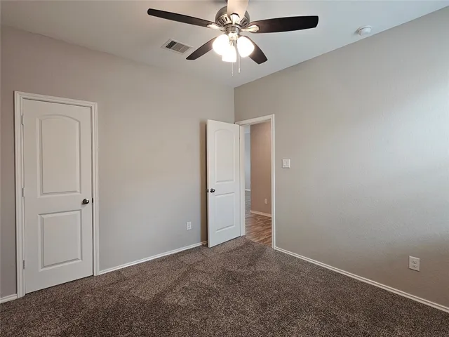 a view of an empty room and chandelier fan
