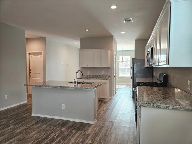 a large kitchen with stainless steel appliances granite countertop a lot of counter space and a sink