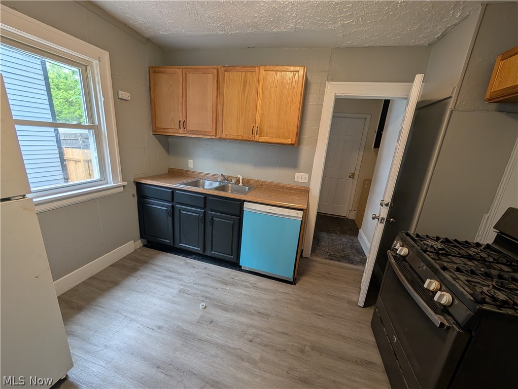 475 East 146th Street Cleveland, OH 44110 - Photo 10 of 28 Kitchen featuring wood-finish flooring, a double basin sink, light wood upper cabinetry, and dark lower cabinetry with a light-colored countertop