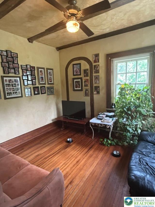 1170 Mosser Road Breinigsville, PA 18031 - Photo 11 of 19 Warm hardwood flooring anchors this cozy living space with exposed ceiling beams and a large window.