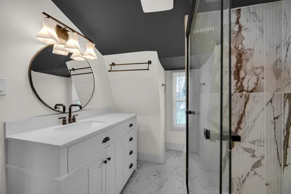 a bathroom with a sink a mirror a vanity and a shower