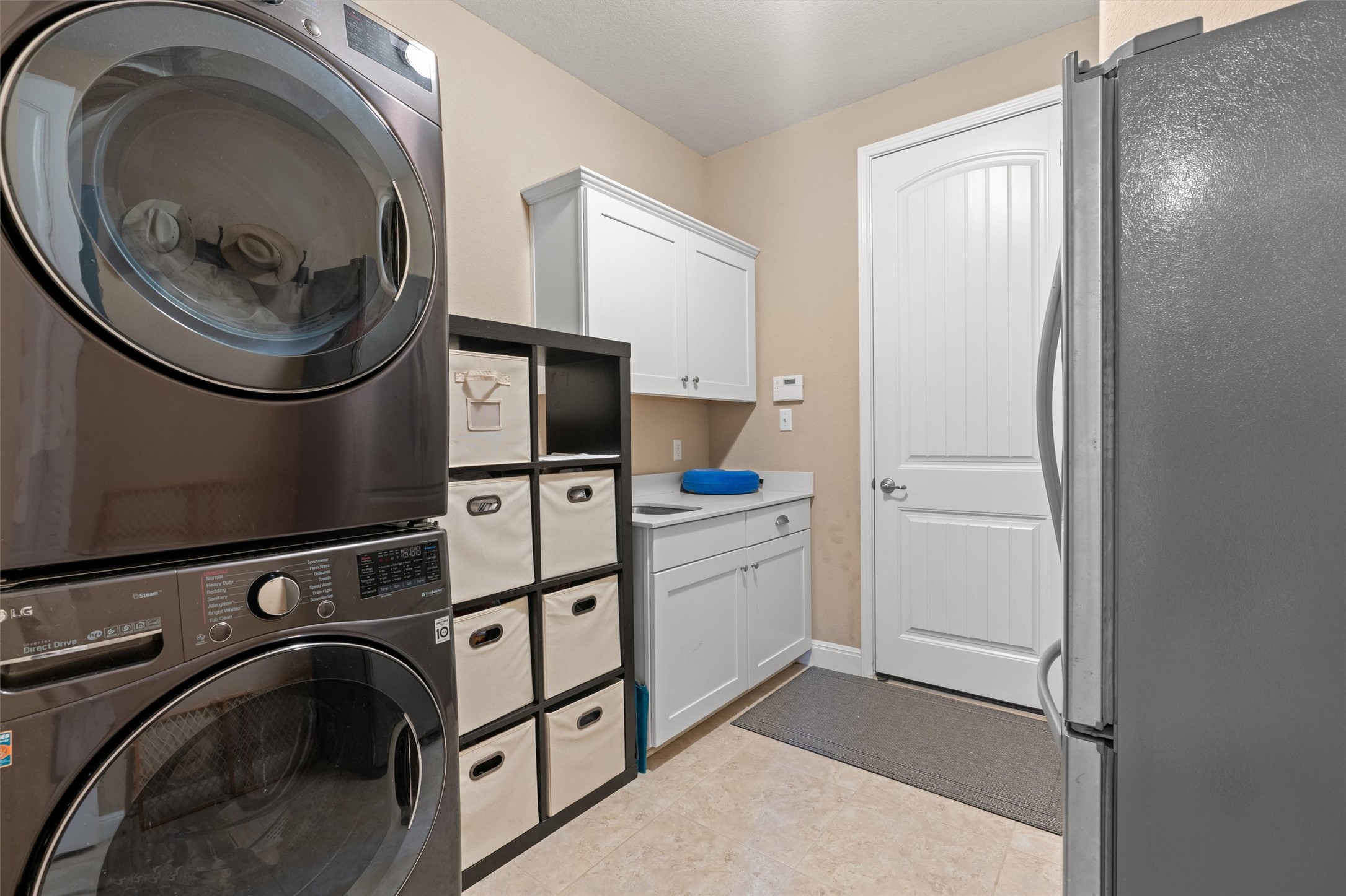 7716 Aria Loop Austin, TX 78736 - Photo 35 of 39 Functional laundry room equipped with stacked appliances and organized storage solutions.