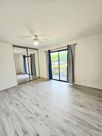 a view of an empty room with a window and wooden floor