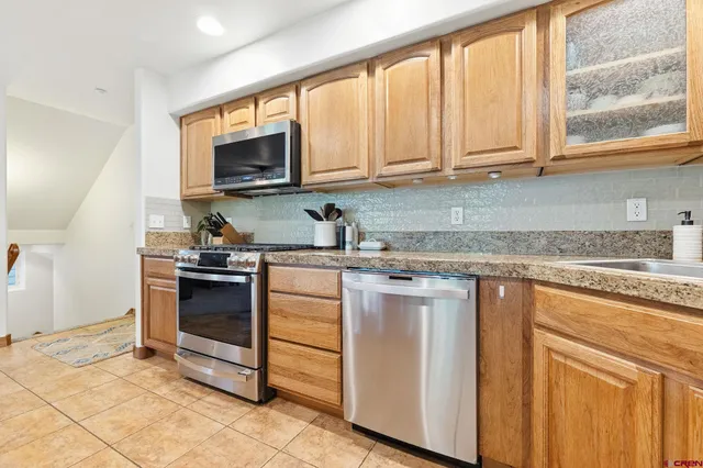 a kitchen with stainless steel appliances granite countertop a stove a sink and a microwave