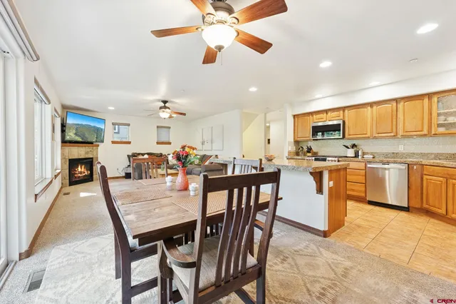 a kitchen with stainless steel appliances kitchen island granite countertop a stove a sink a dining table and chairs
