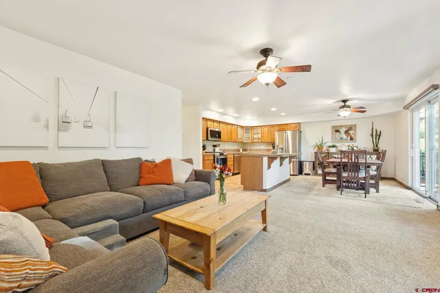 a living room with furniture kitchen view and a chandelier