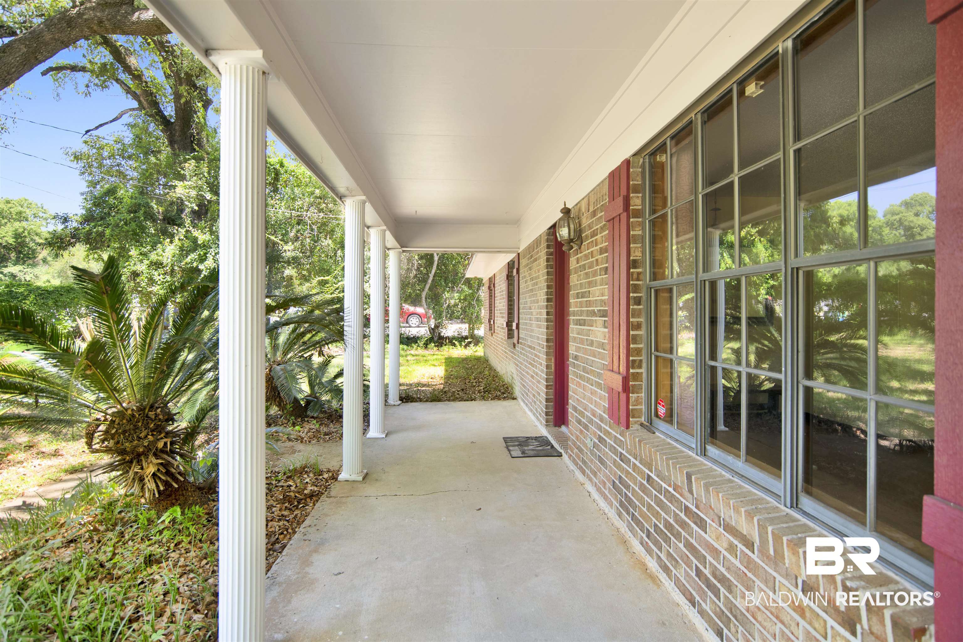 30888 Cemetery Road Daphne, AL 36527 - Photo 4 of 36 Covered front porch featuring fluted columns, a brick exterior, red shutters, gridded windows, and an exterior wall lantern