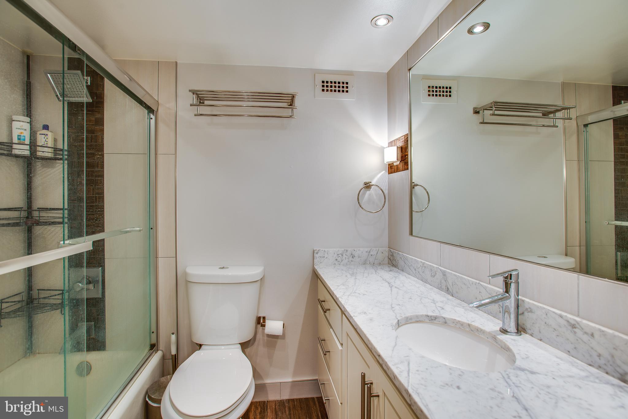 2201 L Street Northwest, Unit 500 Washington, DC 20037 - Photo 18 of 43 a bathroom with a granite countertop sink toilet a mirror and shower