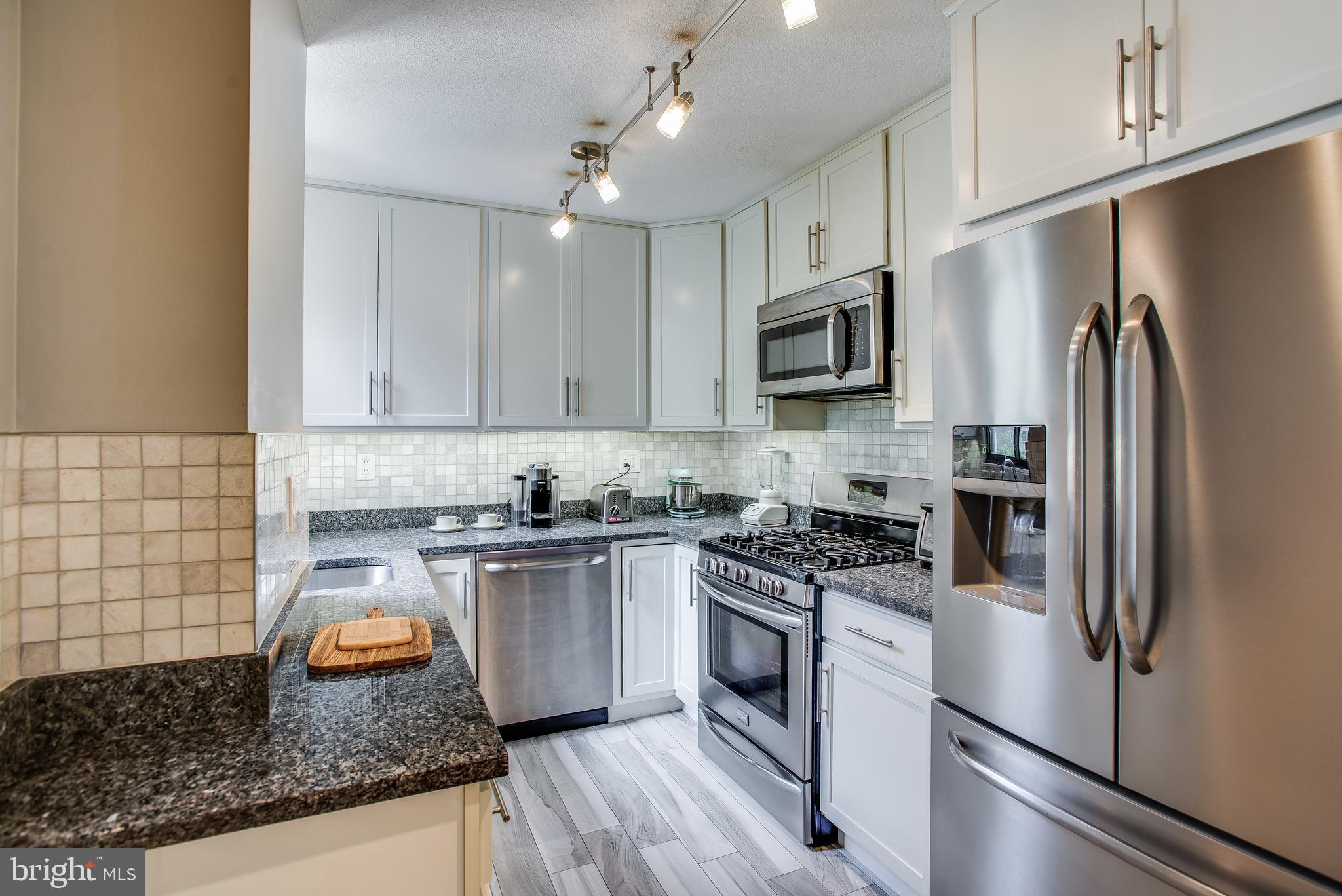 2201 L Street Northwest, Unit 500 Washington, DC 20037 - Photo 5 of 43 a kitchen with granite countertop stainless steel appliances and wooden cabinets