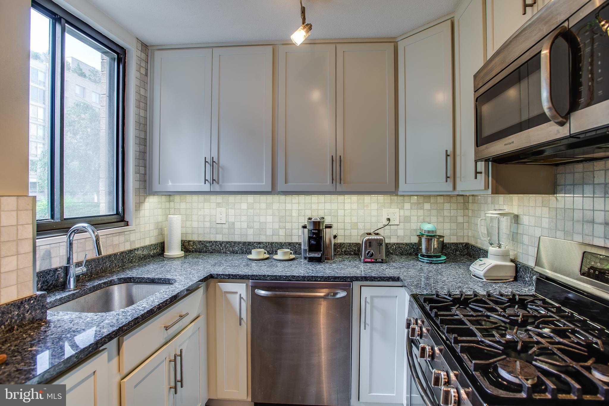 2201 L Street Northwest, Unit 500 Washington, DC 20037 - Photo 6 of 43 a kitchen with granite countertop a sink stove and cabinets