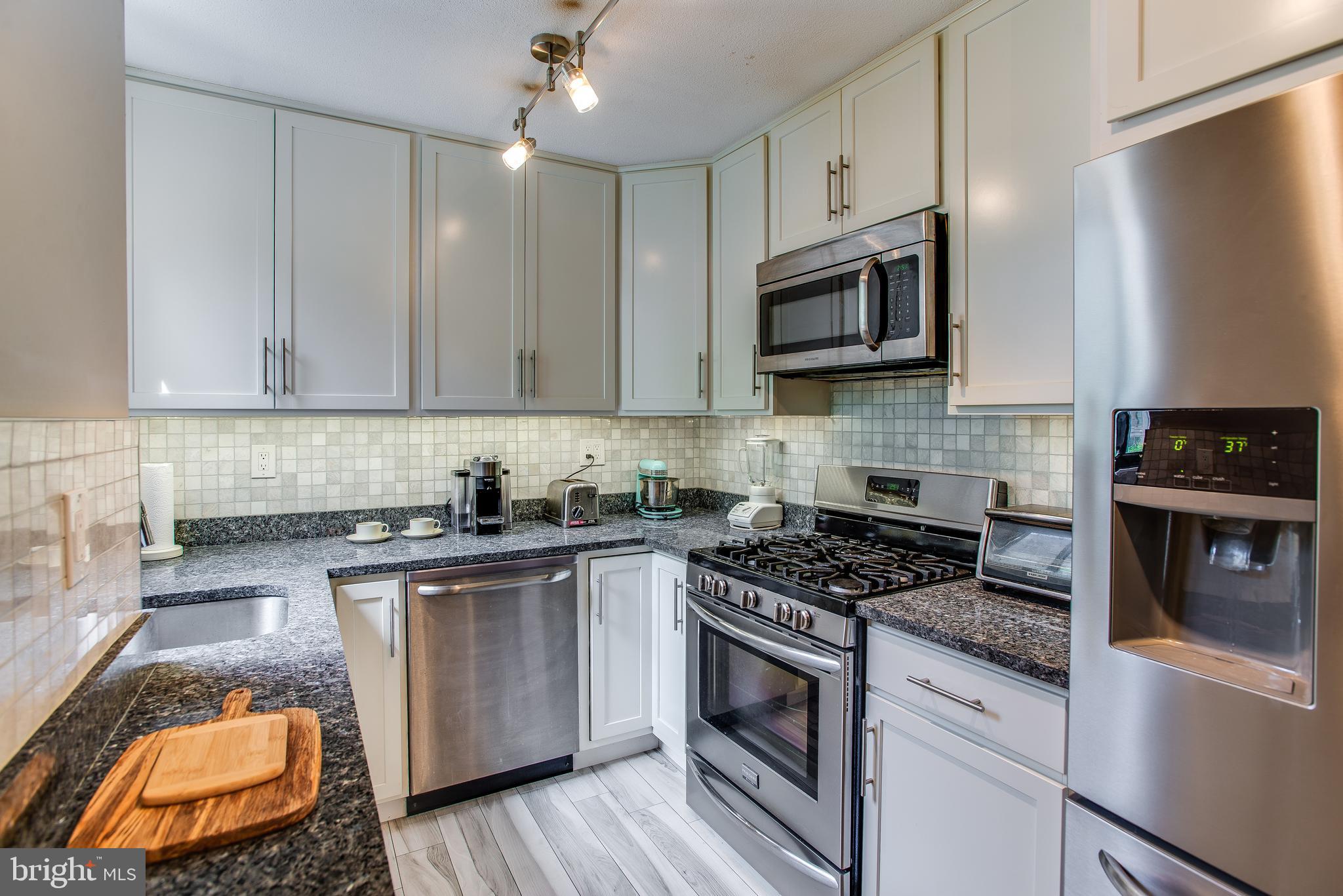 2201 L Street Northwest, Unit 500 Washington, DC 20037 - Photo 7 of 43 a kitchen with stainless steel appliances granite countertop a stove a sink and a microwave