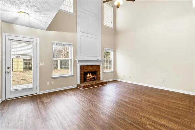 a view of an empty room with wooden floor and a fireplace