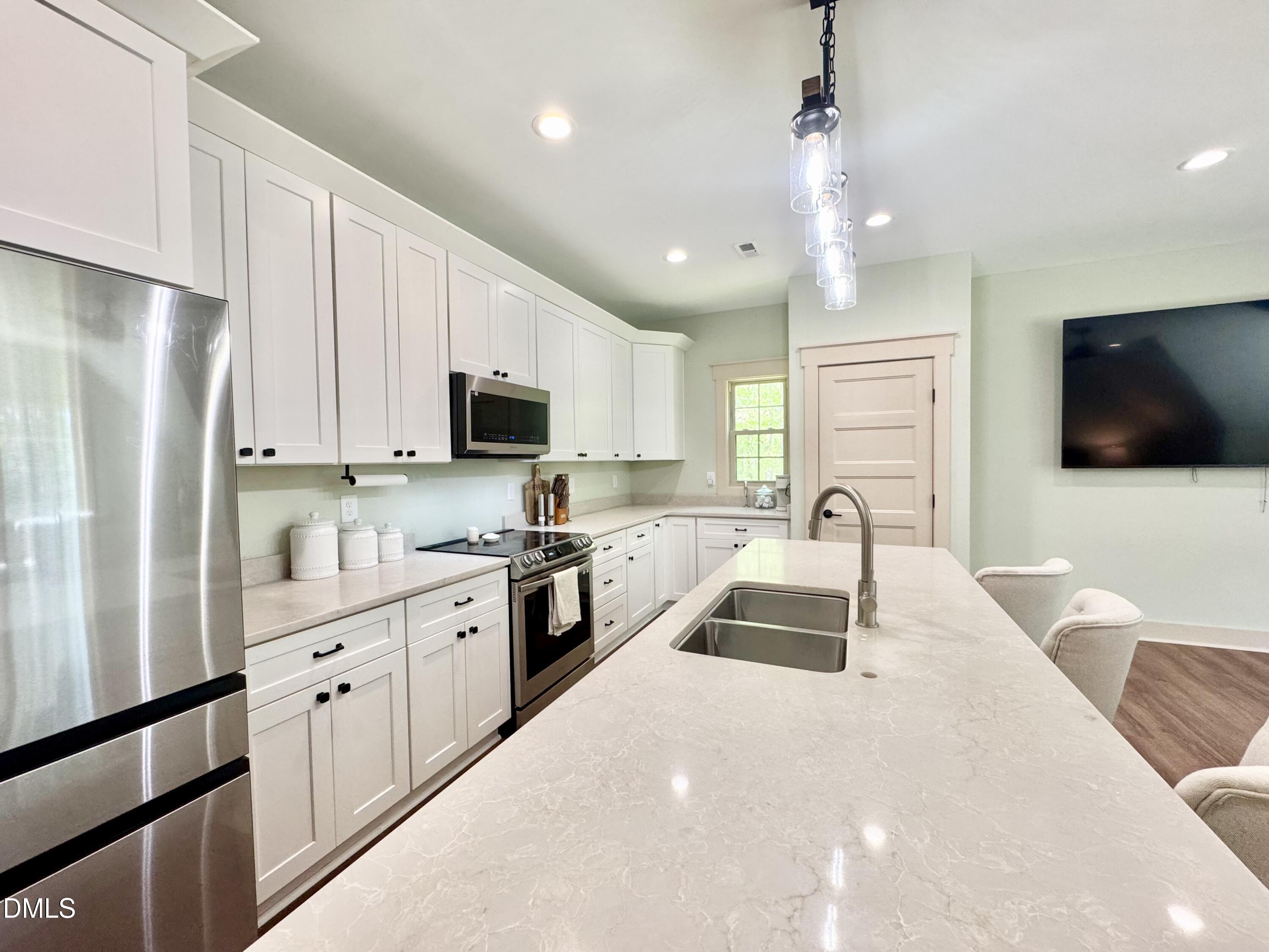 254 Fairway Drive Roxboro, NC 27574 - Photo 10 of 28 a kitchen with granite countertop a refrigerator stove a sink and white cabinets with wooden floor