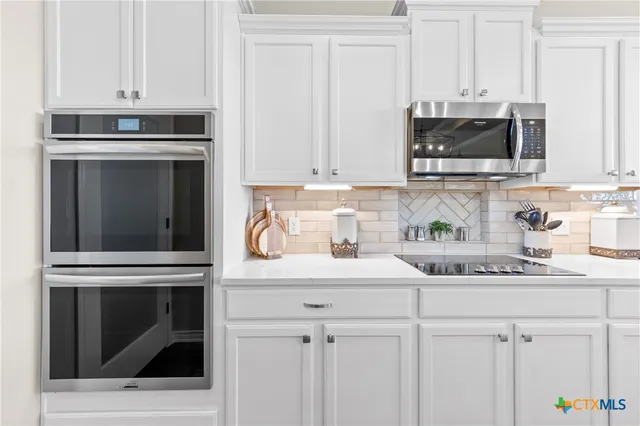 a kitchen with stainless steel appliances a sink dishwasher stove refrigerator and cabinets with wooden floor