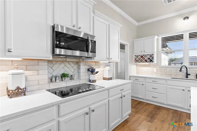 a kitchen with stainless steel appliances a dining table chairs refrigerator and microwave