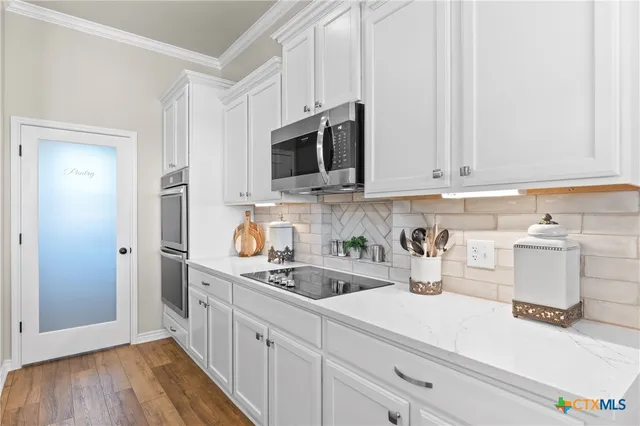 a kitchen with white cabinets and window