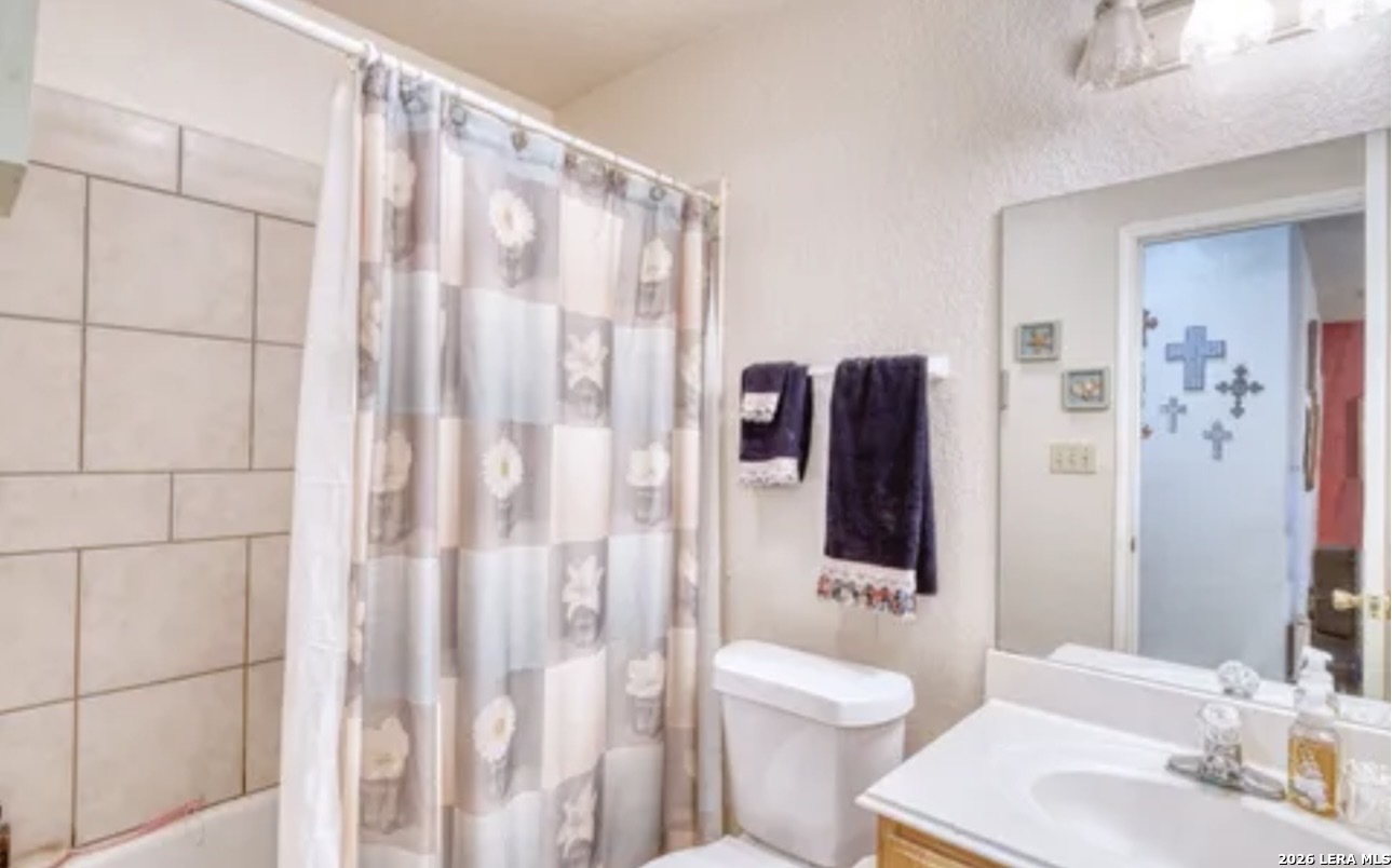 622 South Oak Street Pearsall, TX 78061 - Photo 16 of 22 a bathroom with a toilet sink and shower curtain