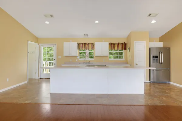 a large white kitchen with kitchen island a refrigerator and a sink