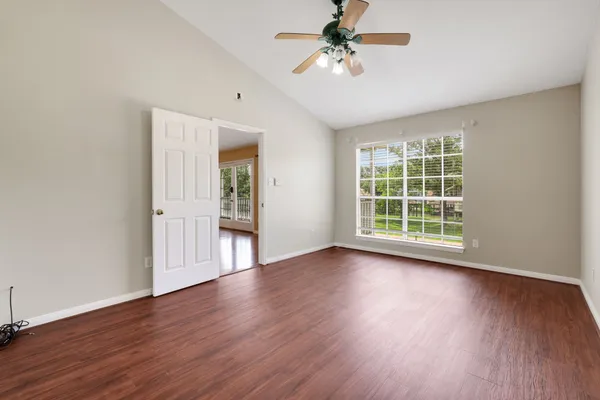 a view of an empty room with a window and wooden floor