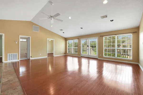 a view of an empty room with wooden floor and a window